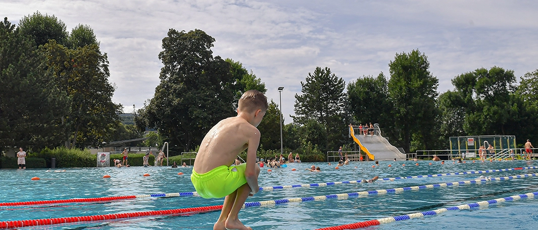 Ein Kind springt in das Schwimmbecken im Ostbad
