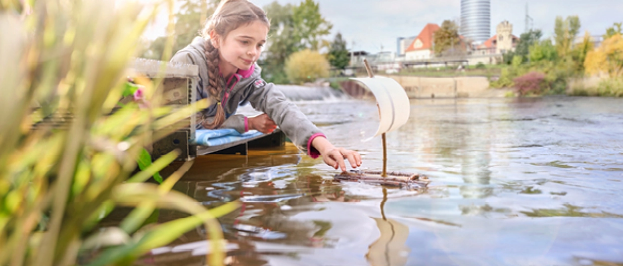 Mädchen spielt mit kleinem Boot am Ufer des Flusses Saale. Mädchen spielt mit kleinem Boot am Ufer des Flusses Saale.