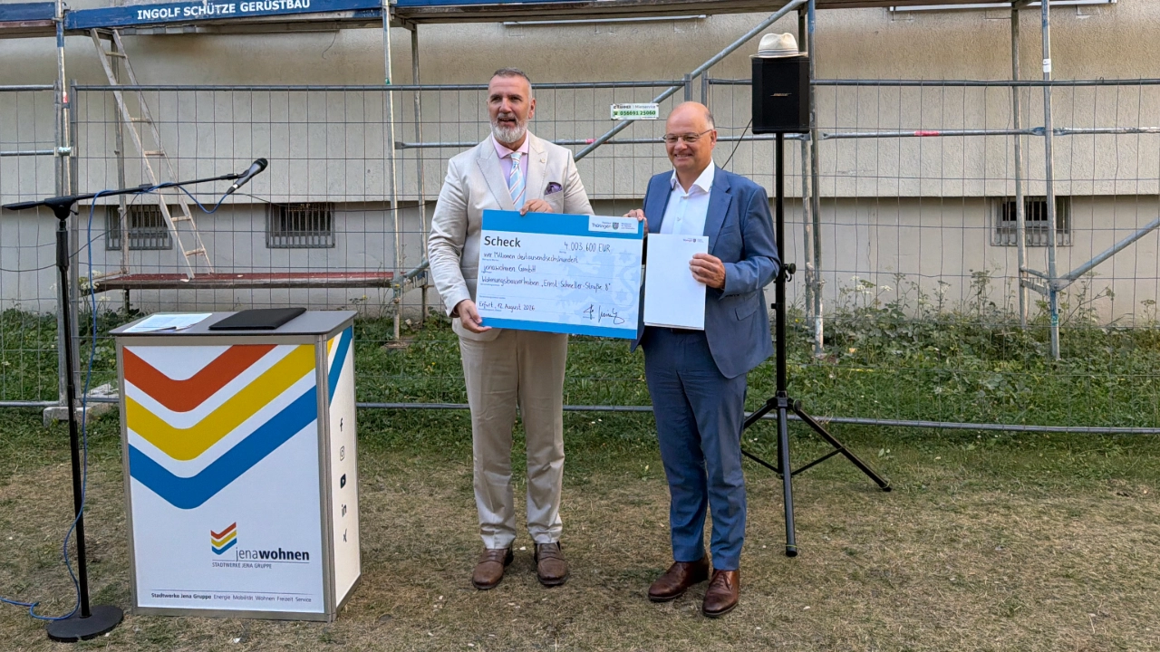 Fördermittelübergabe für die Ernst-Schneller-Straße 8 in Jena-Lobeda: Thüringens Minister für Digitales und Infrastruktur, Steffen Schütz, übergibt den Scheck an jenawohnen Geschäftsführer Tobias Wolfrum 