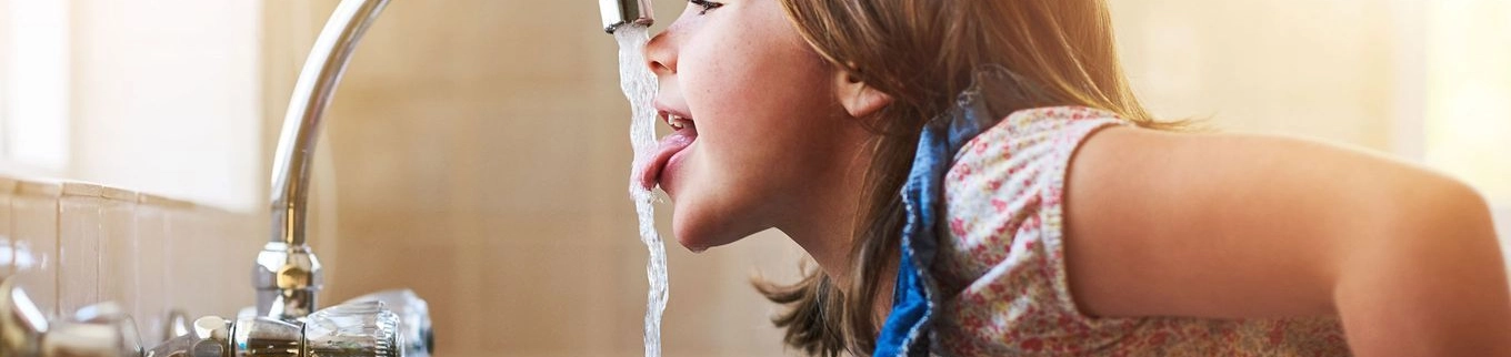 Kind trinkt aus einem Wasserhahn