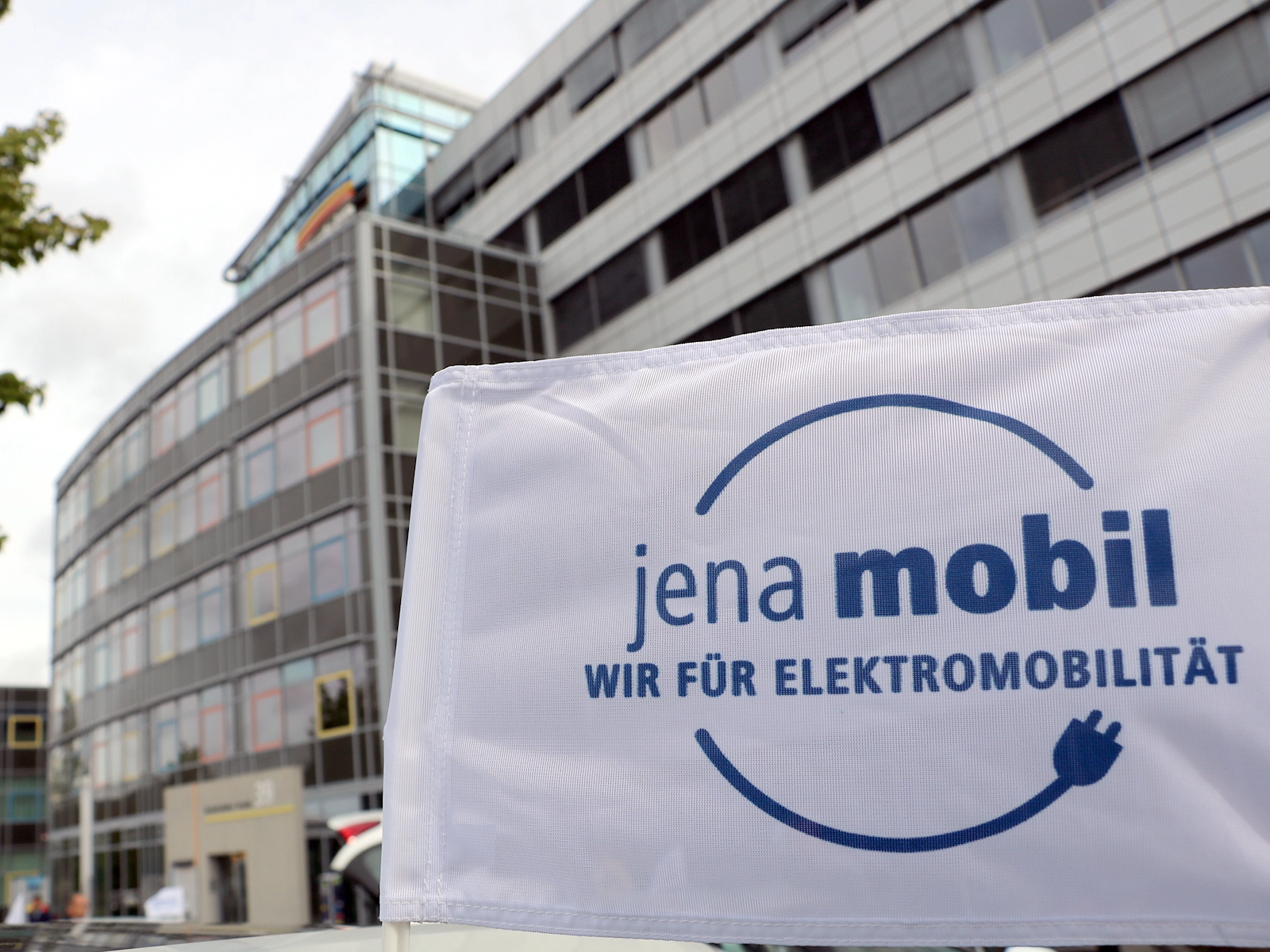 Fahne mit Projektlogo Wir für Elektromobilität vor dem Stadtwerke-Gebäude