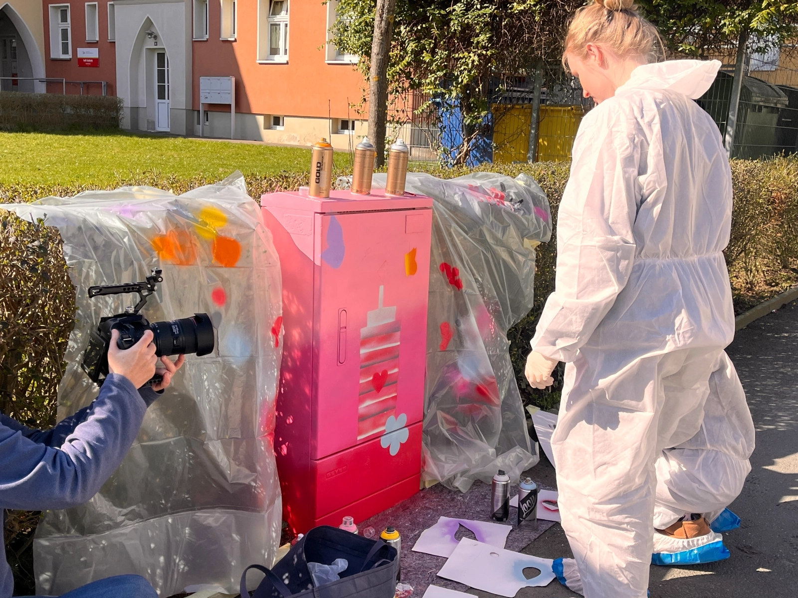 Eine Schülerin verschönert einen Stromkasten mit Graffiti. 