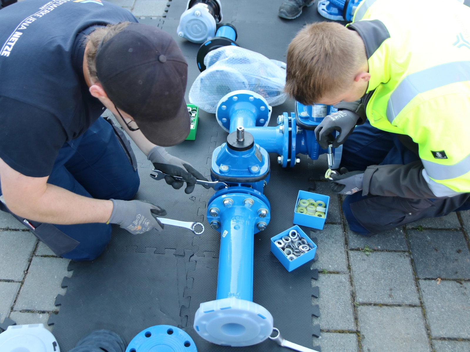 Mitarbeitende der Stadtwerke Jena Netze schrauben große blaue Trinkwasserrohre zusammen Mitarbeitende der Stadtwerke Jena Netze schrauben große blaue Trinkwasserrohre zusammen