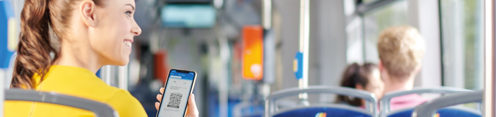 Eine Frau sitzt in der Bahn und hält ein Handy mit dem Deutschland-Ticket.