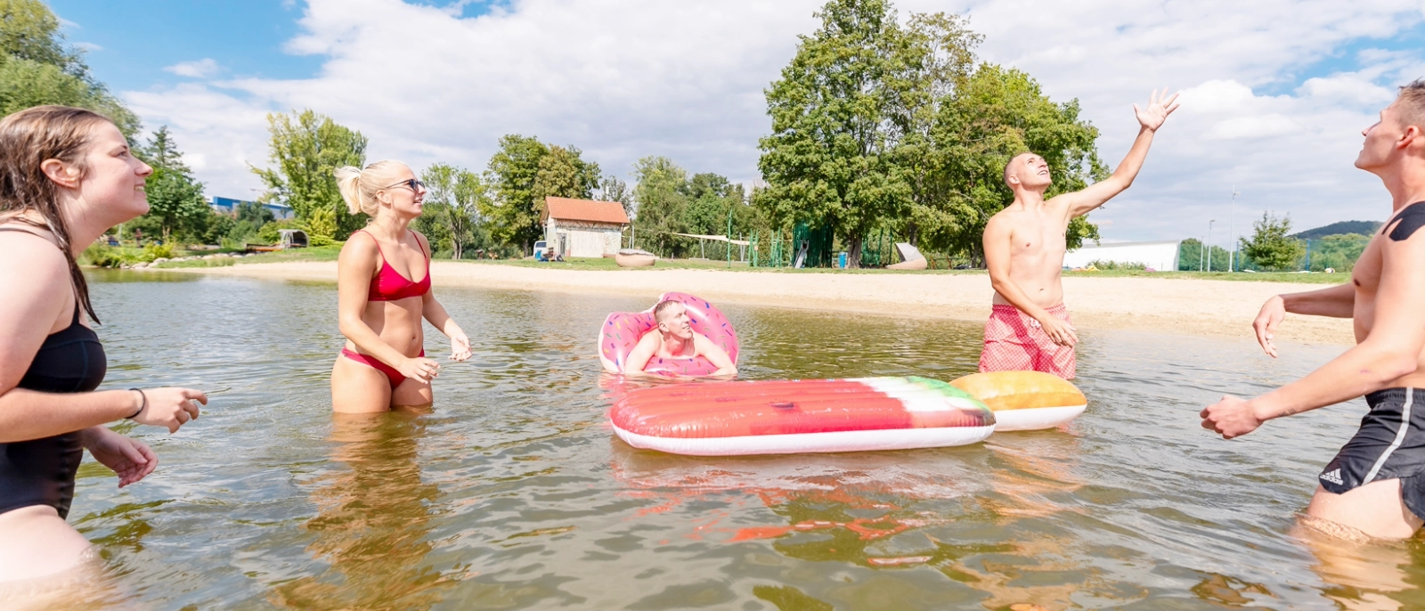Badegäste spielen mit einem Ball im Schleichersee.