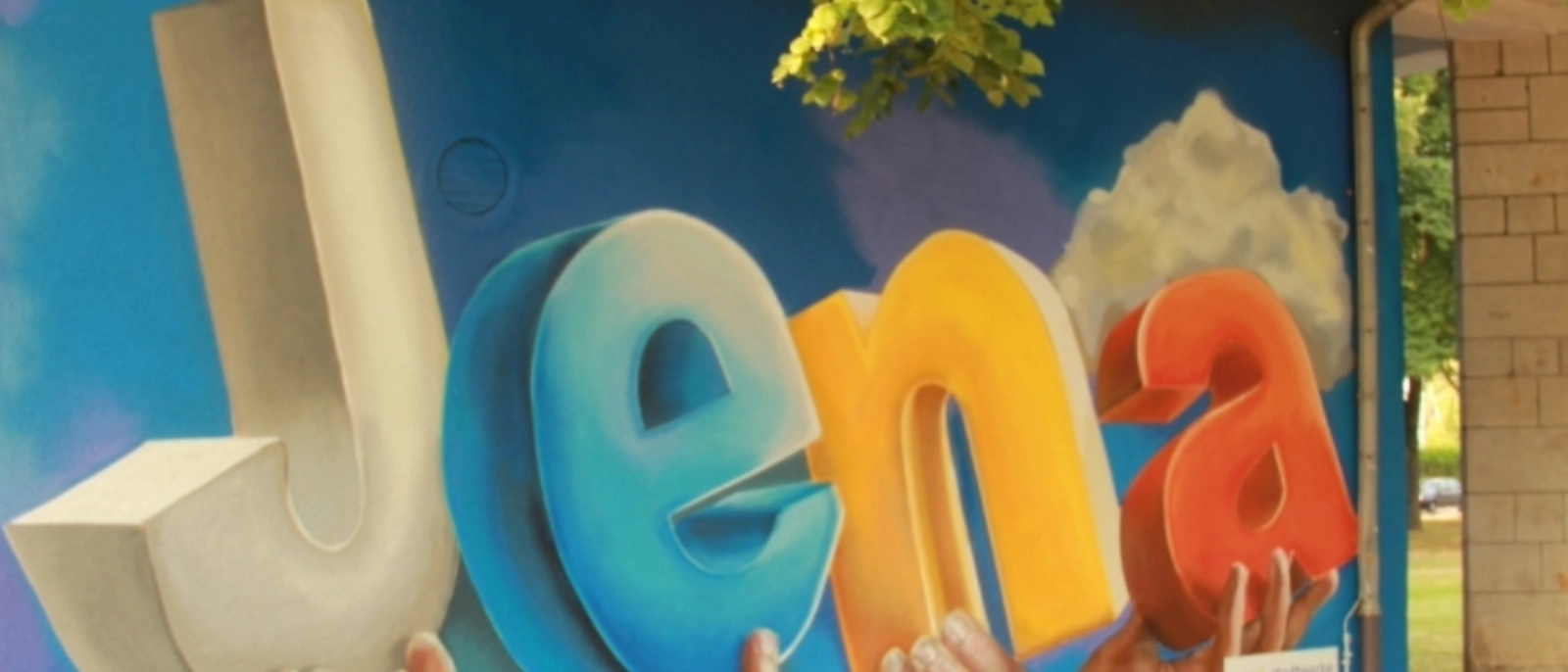 Trafostation am Jenaplan: Die Worte „Wir für Jena und die Region“ als Leitspruch der Stadtwerke Energie Jena-Pößneck sind über die vier Wände des Gebäudes verteilt.