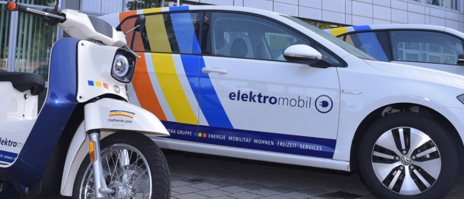 E-Schwalbe und E-Auto vor dem Stadtwerke-Haus