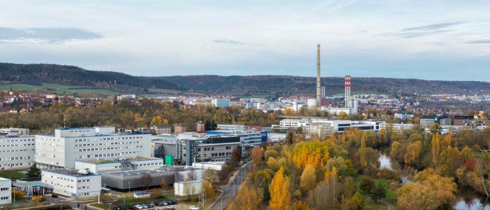 Panoramaansicht von Lobeda, Göschwitz, Teilen von Winzerla und dem Gewerbegebiet Jena21 in Jena mit Gewerbeflächen, Gebäuden und angrenzenden Grünbereichen.