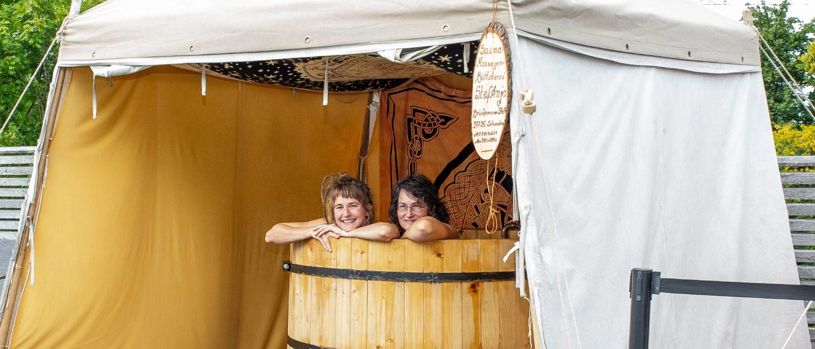 Zwei Frauen sitzen in einem Badezuber, einem beheiztem Badefass. 