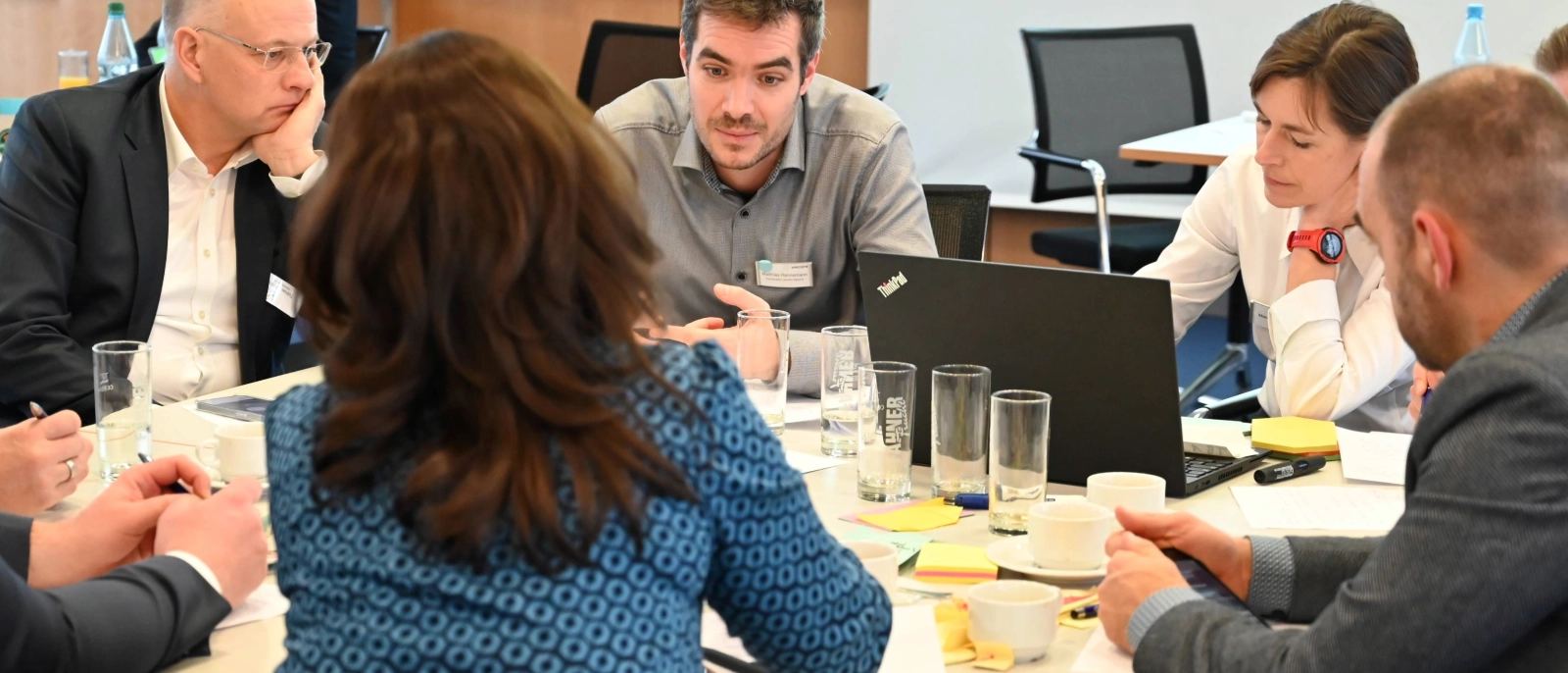 Fünf Personen sitzen während eines Innovationsworkshops am Tisch und beraten sich.