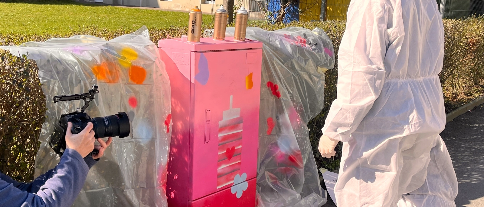 Eine Schülerin verschönert einen Stromkasten mit Graffiti. 