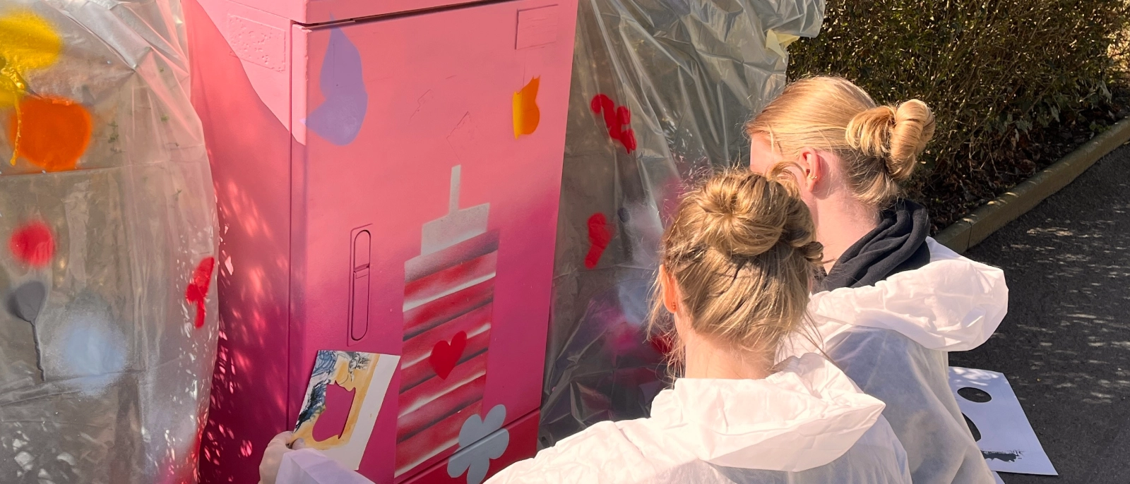 Schülerinnen verschönern einen Stromkasten.