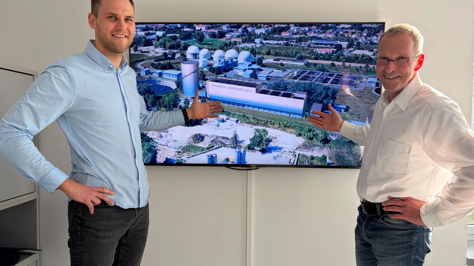 Projektleitung (©Stadtwerke Jena, Tina Schnabel): Die Planungen für ANIKA werden konkret: Die Projektleiter Jonas Waldhäusl (links), verantwortlich für die Planung der Energiezentrale, und Götz Blankenburg, verantwortlich für die Leitungsplanung, vor einer Visualisierung der Energiezentrale. 