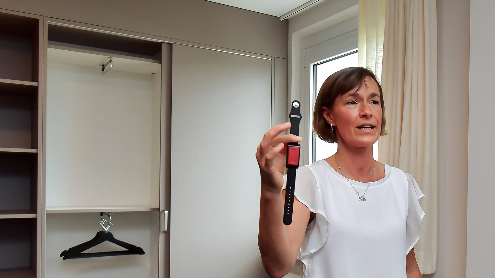 Eine Frau steht im Innenraum des smarten Quartiers mit einer Uhr in der Hand.