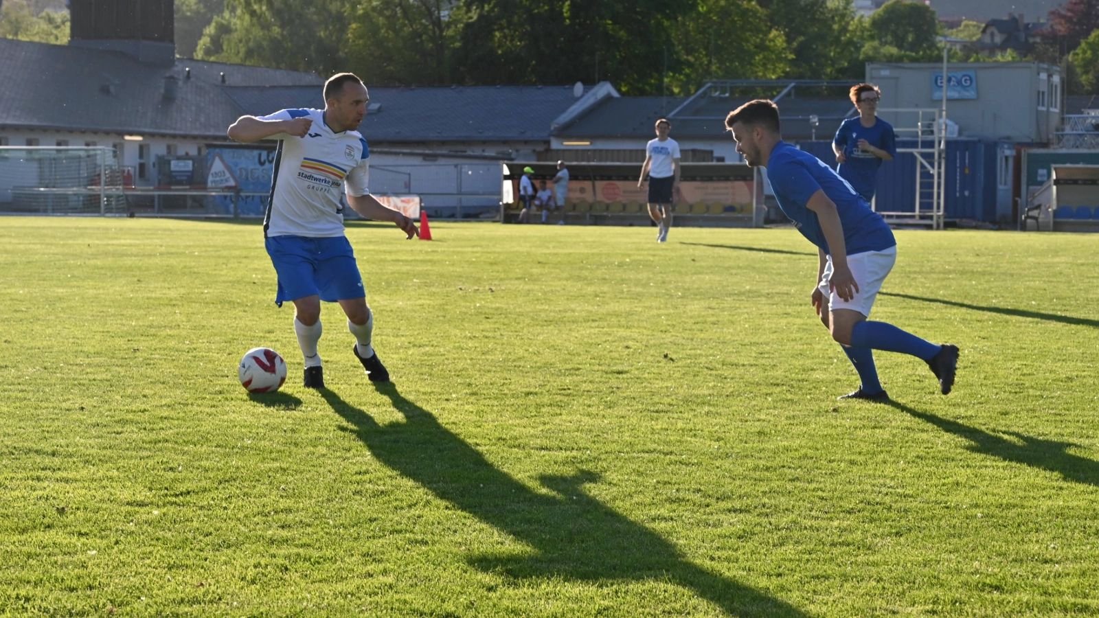 Zwei Fußballspieler im Zweikampf auf dem Rasen. 