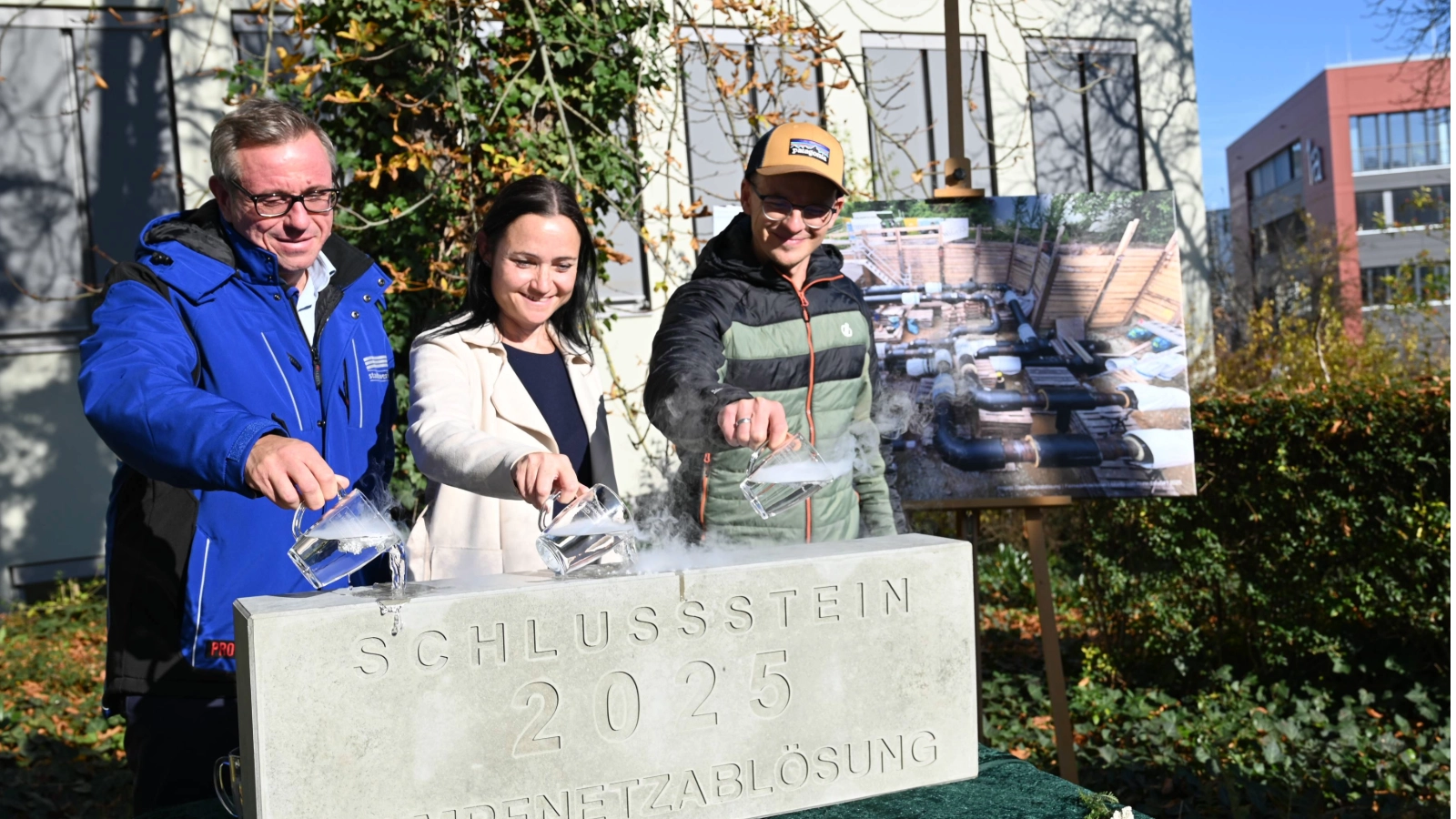 Passenderweise mit einem Schwall heißem Wasser begossen Stadtwerke Energie Geschäftsführer André Sack, Stadtwerke Jena Netze-Geschäftsführerin Kristin Weiß und Stadtwerke-Projektleiter Christoph Krauße (v.l.) den Schlussstein für das Projekt Dampfnetzablösung.