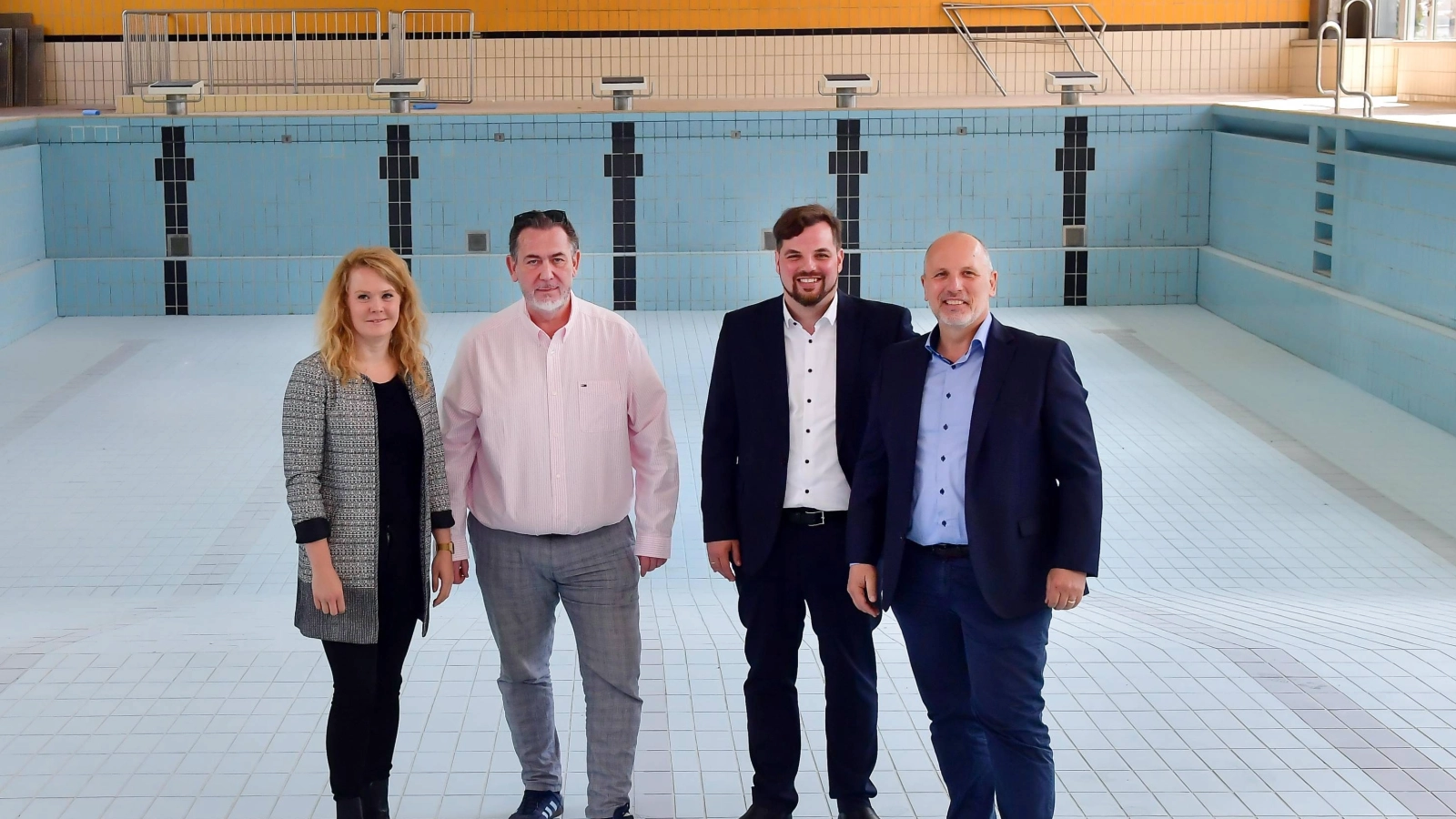 Gruppenbild im Becken: Im leeren Becken der ehemaligen Schwimmhalle Lobeda-West: Katrin Hitziggrad von „Blank – Agentur für Zwischennutzung“, Jörg Hühn, Geschäftsführer der reCoVer Stiftung Jena, Johannes Schleußner, Dezernent für Bildung, Jugend, Kultur und Sport, und Bernhard Dengel, Geschäftsführer der Jenaer Bäder (v. l. n. r.), informierten beim Pressetermin über die nächsten Schritte für die zukünftige Entwicklung der Halle.