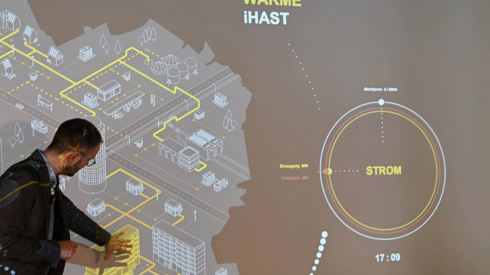Christian Dornack von den Stadtwerken Jena Netzen zeigt auf digitale Visualisierung eines Energiekonzepts mit Wärme‑ und Stromflussdiagrammen