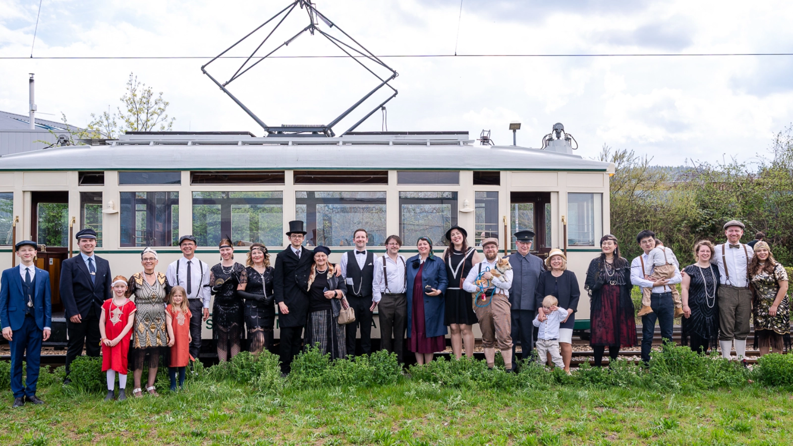 Gäste versammeln sich vor historischen Straßenbahnen 