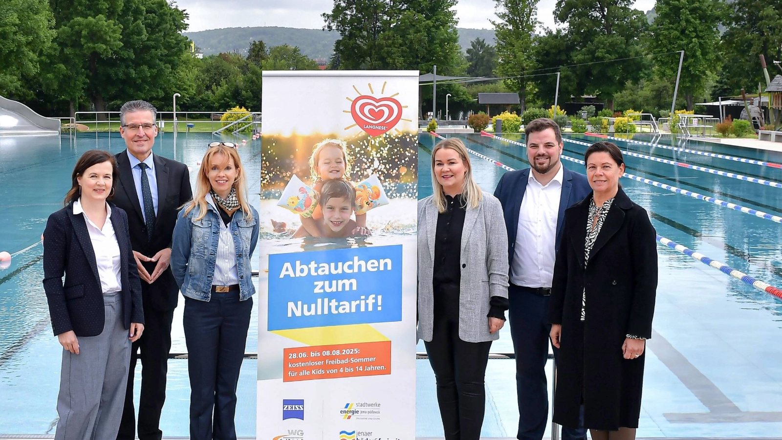 Präsentierten gemeinsam die Sponsoring-Sommerferienaktion 2025 im Jenaer Ostbad: v.l. Beatrice Weinberger (Pressesprecherin Carl Zeiss AG), Andreas Deiß (Vorstand WG Carl Zeiss eG), Ines Eckert (Leiterin Unternehmenskommunikation Stadtwerke Jena GmbH), Susan Zetzmann (Geschäftsführerin Jenaer Bäder und Freizeit GmbH), Johannes Schleußner, Vorsitzender des Bäderbeirats und Dezernent für Bildung, Jugend, Kultur und Sport und Simone Uhlemann (Leiterin Marketing/Öffentlichkeitsarbeit WG Carl Zeiss eG). 