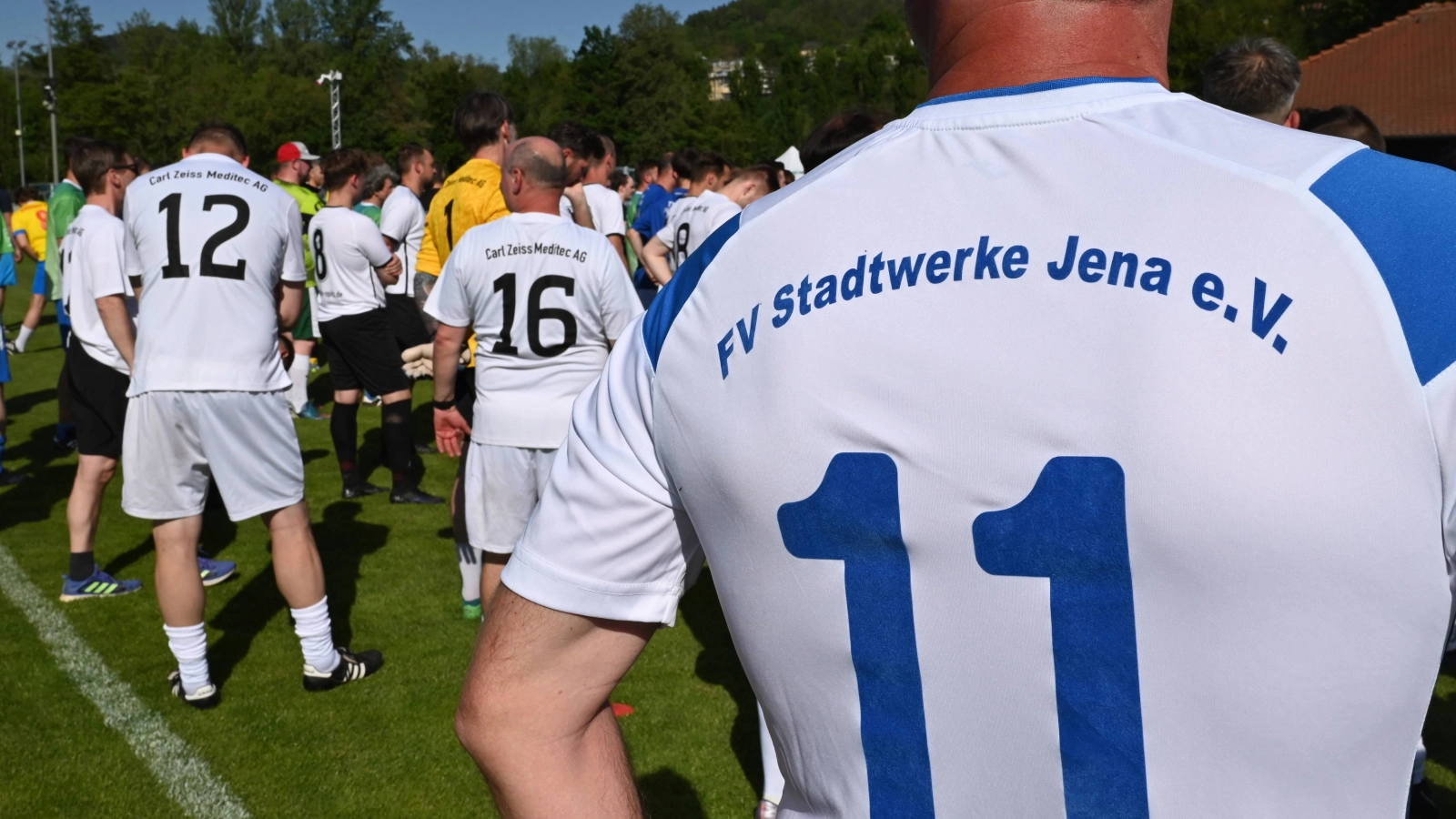 Die Teilnehmer des Fußballturniers stehen auf dem Rasen.