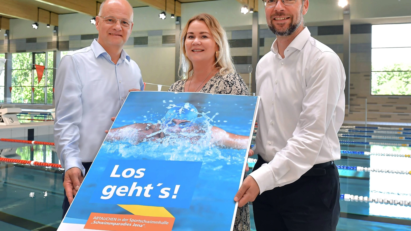Drei Personen halten ein Plakat der Jenaer Bäder in den Händen