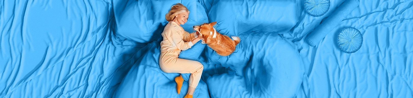 Frau mit Hund liegen auf einem hellblauen Untergrund