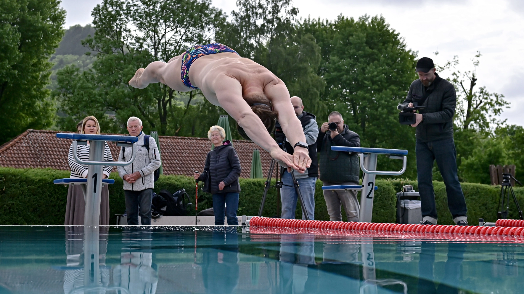 Ein Mann springt von einem Startblock in ein Wasserbecken