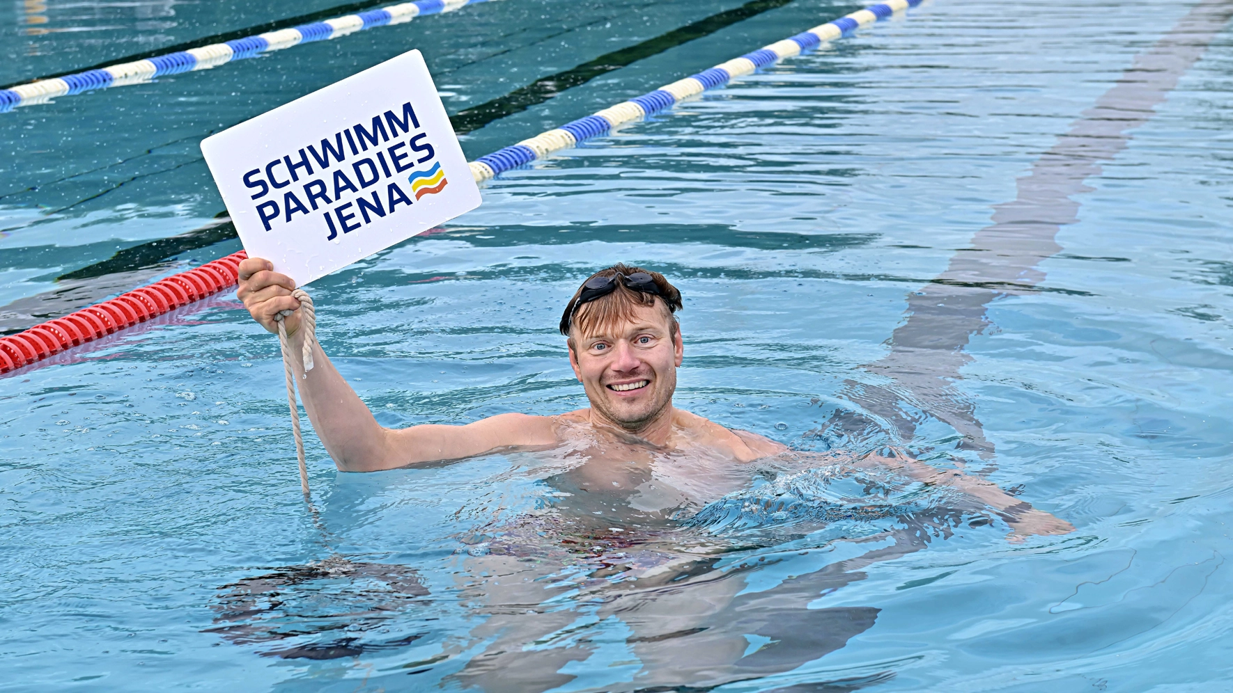 Ein Mann im Wasser mit einem Schild in der Hand 