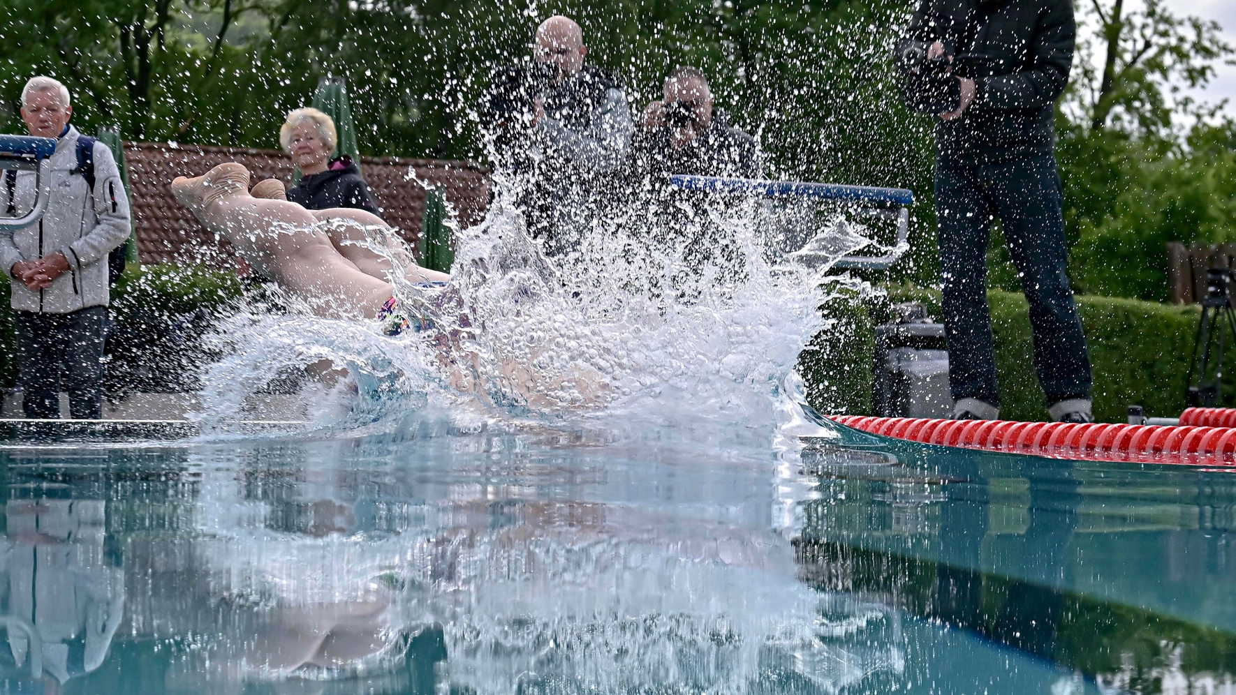 Ein Mann springt von einem Startblock in ein Wasserbecken