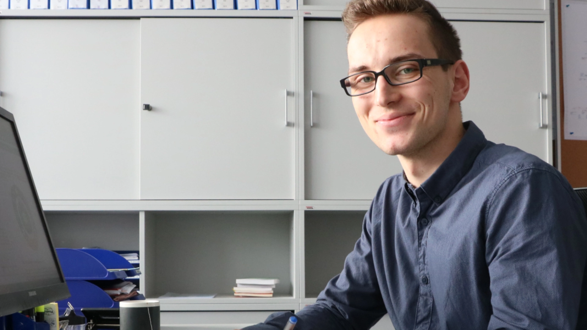 Ein junger Mann sitzt im Büro vor seinem Computer