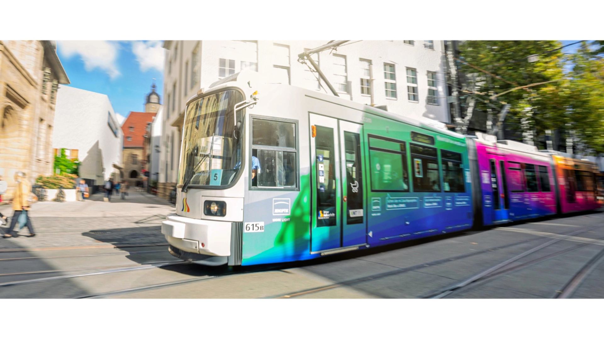 Straßenbahn fährt durch die Straßen von Jena mit Außenwerbung.