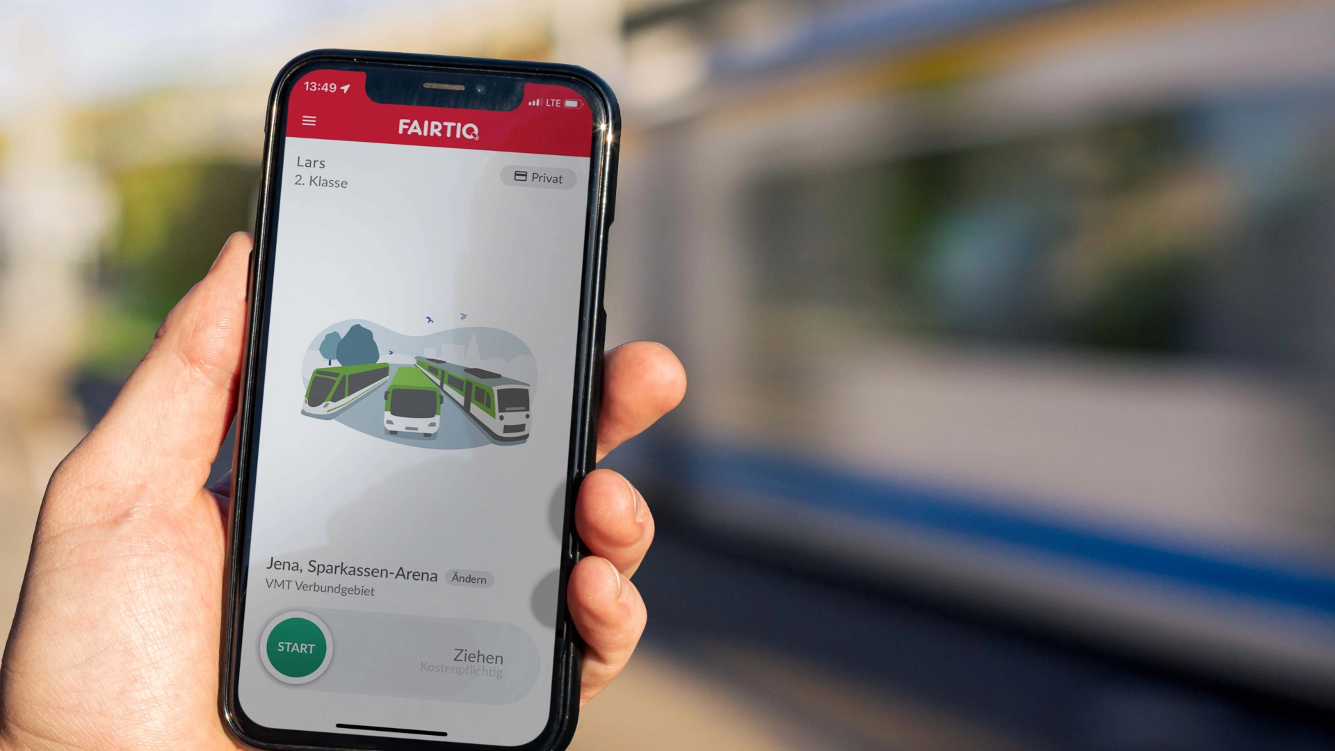 Jemand hält ein Handy in der Hand mit der geöffneten Fairtiq-App an der Haltestelle. Eine Straßenbahn fährt im Hintergrund vorbei.