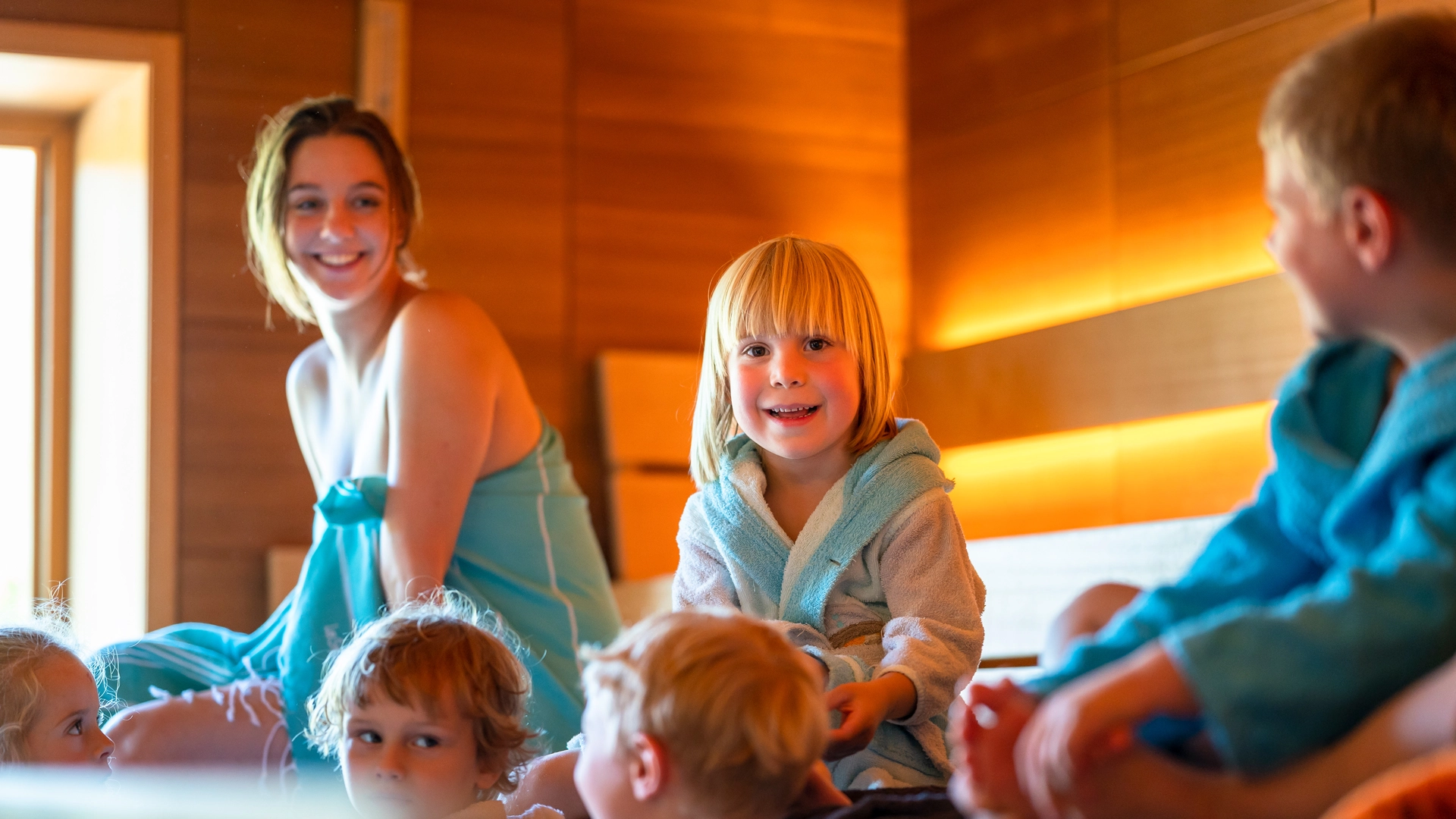 Eine Frau und fünf Kinder sitzen in einer Sauna