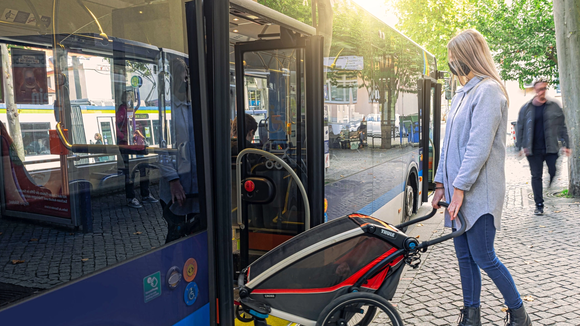 Eine Frau schiebt einen Kinderwagen in den Bus.