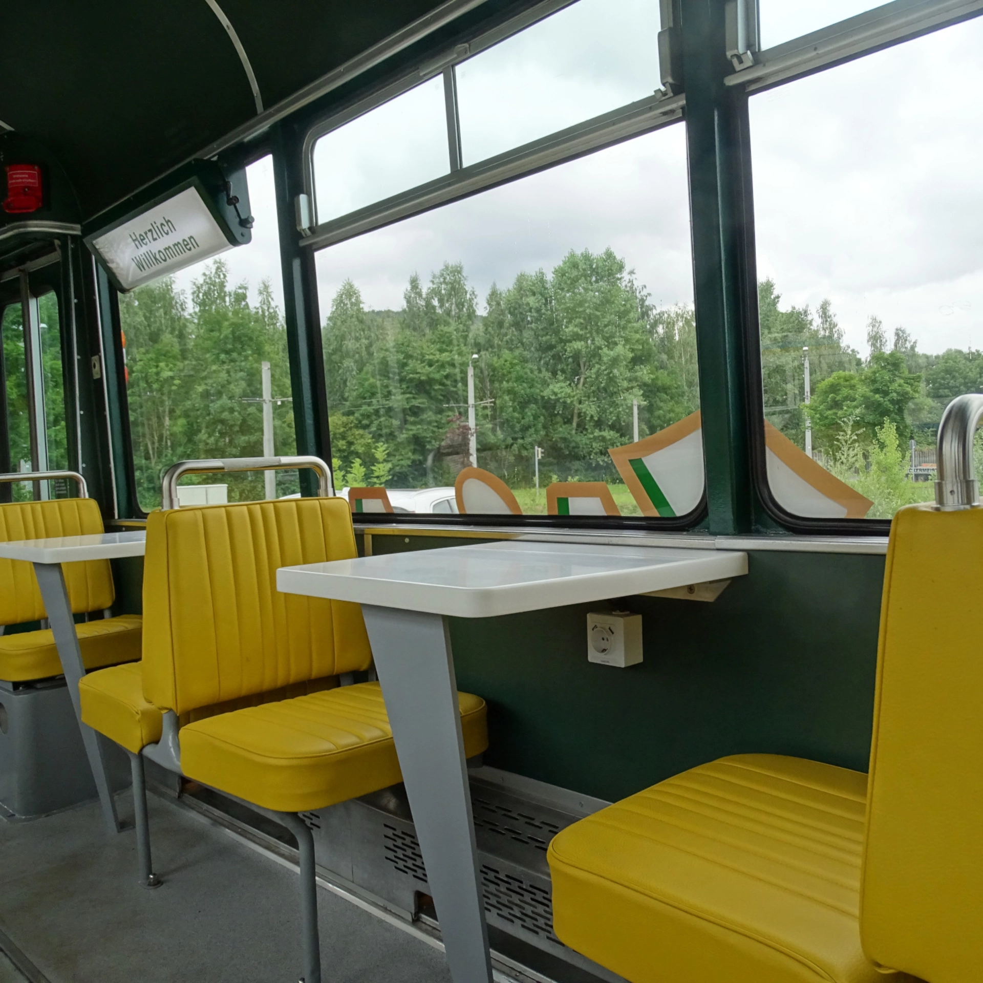 Eine Innenaufnahme der Ur-Krostitzer Partybahn. Zu sehen sind gelbe Sitze und weiße Tische.