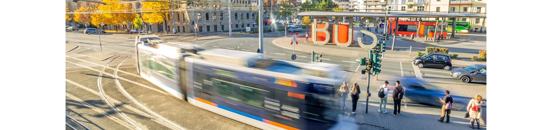 Eine fahrende Straßenbahn vor dem Busbahnhof in Jena. Im Hintergrund das Volksbad.