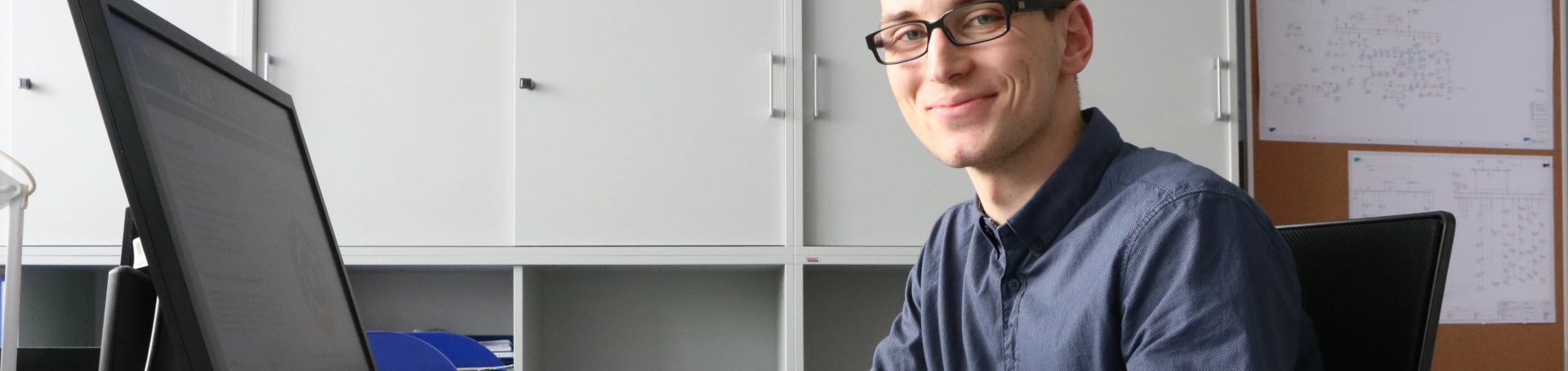Ein junger Mann sitzt im Büro vor seinem Computer