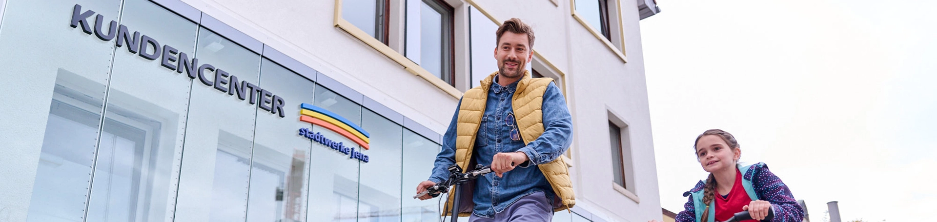 Zwei Personen fahren jeweils auf einem Roller am Stadtwerke Jena Kundencenter vorbei