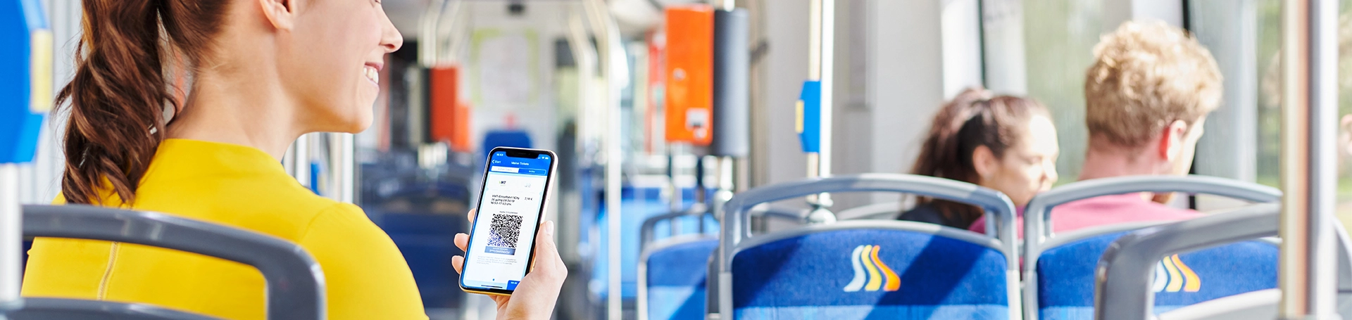 Eine Frau sitzt mit ihrem Handy in der Straßenbahn.