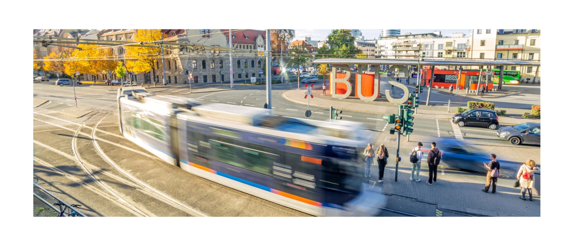 Eine fahrende Straßenbahn vor dem Busbahnhof in Jena. Im Hintergrund das Volksbad.