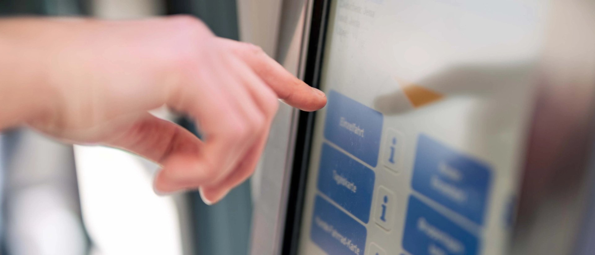 Eine Hand tippt auf das Display eines Fahrscheinautomaten im Fahrzeug.