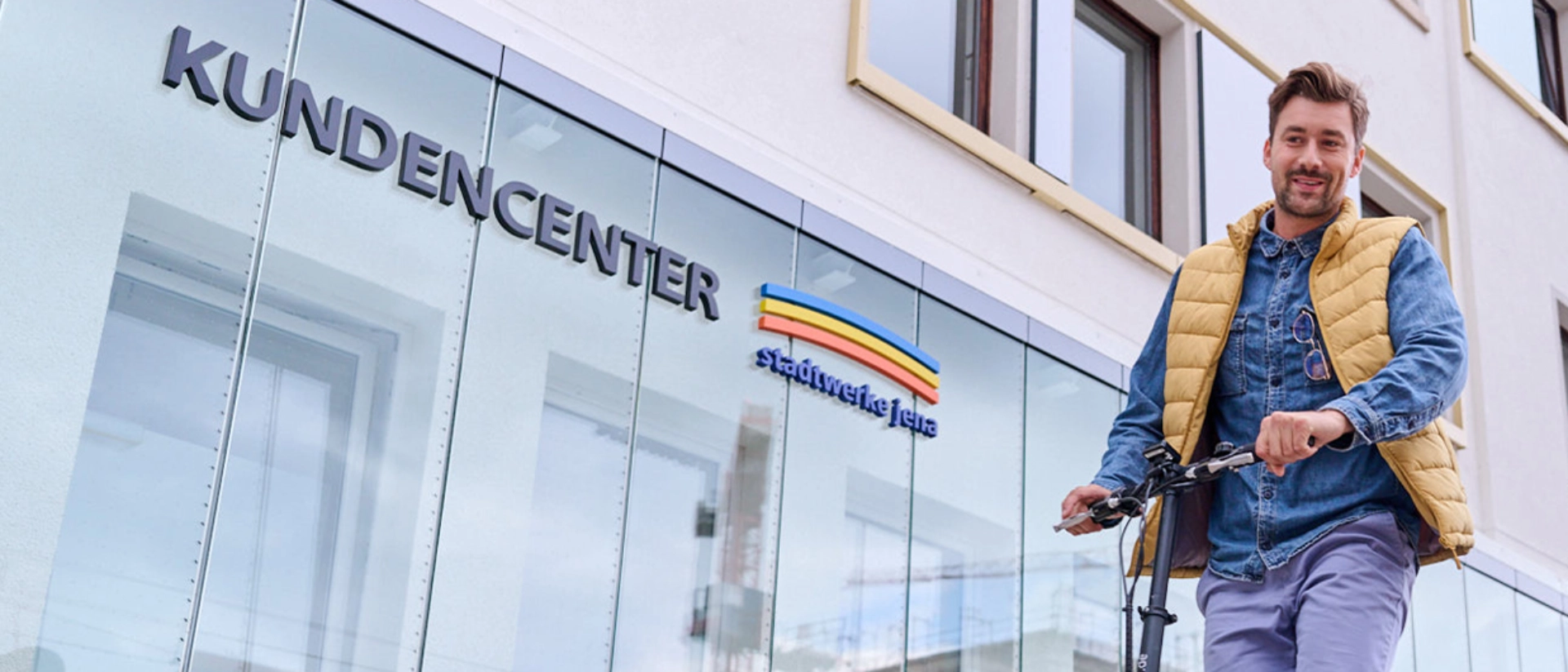 Zwei Personen fahren jeweils auf einem Roller am Stadtwerke Jena Kundencenter vorbei