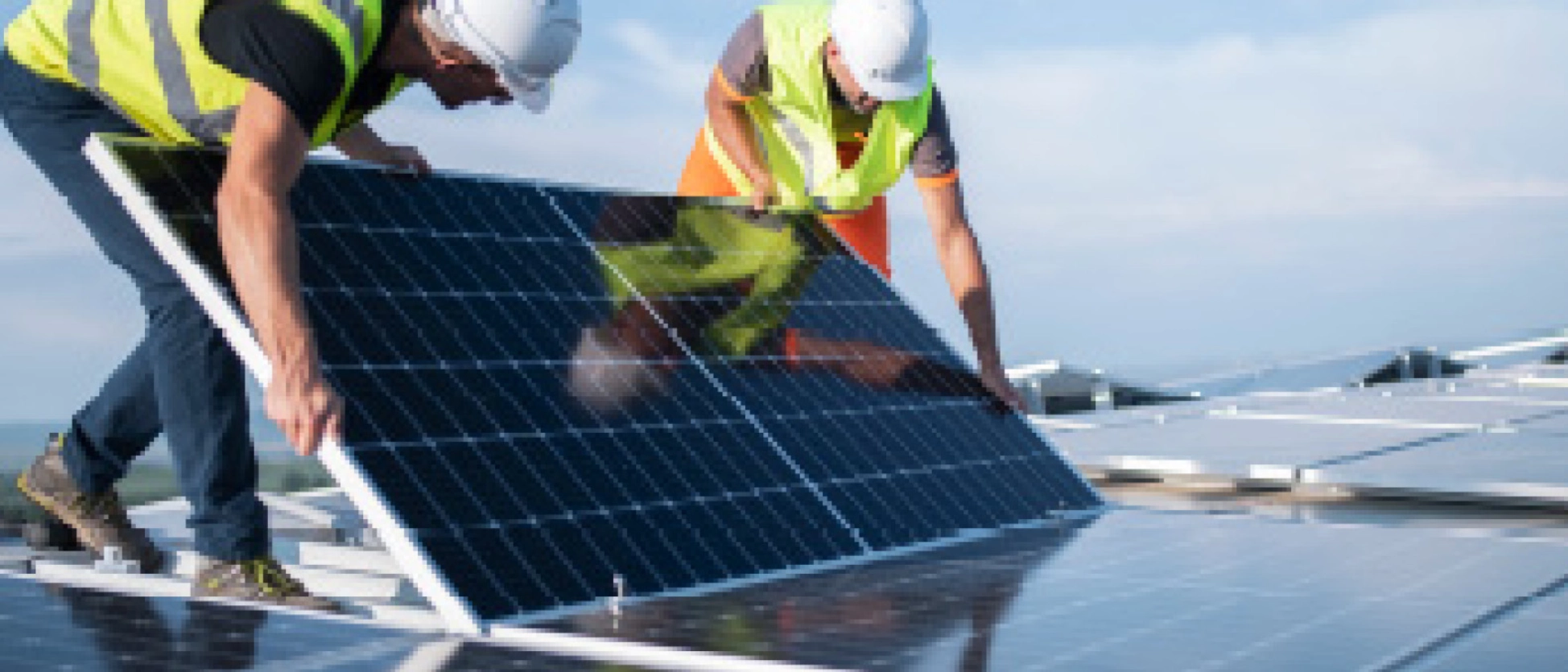 Zwei Arbeiter platzieren ein Solar-Modul auf einer großen Dachfläche.