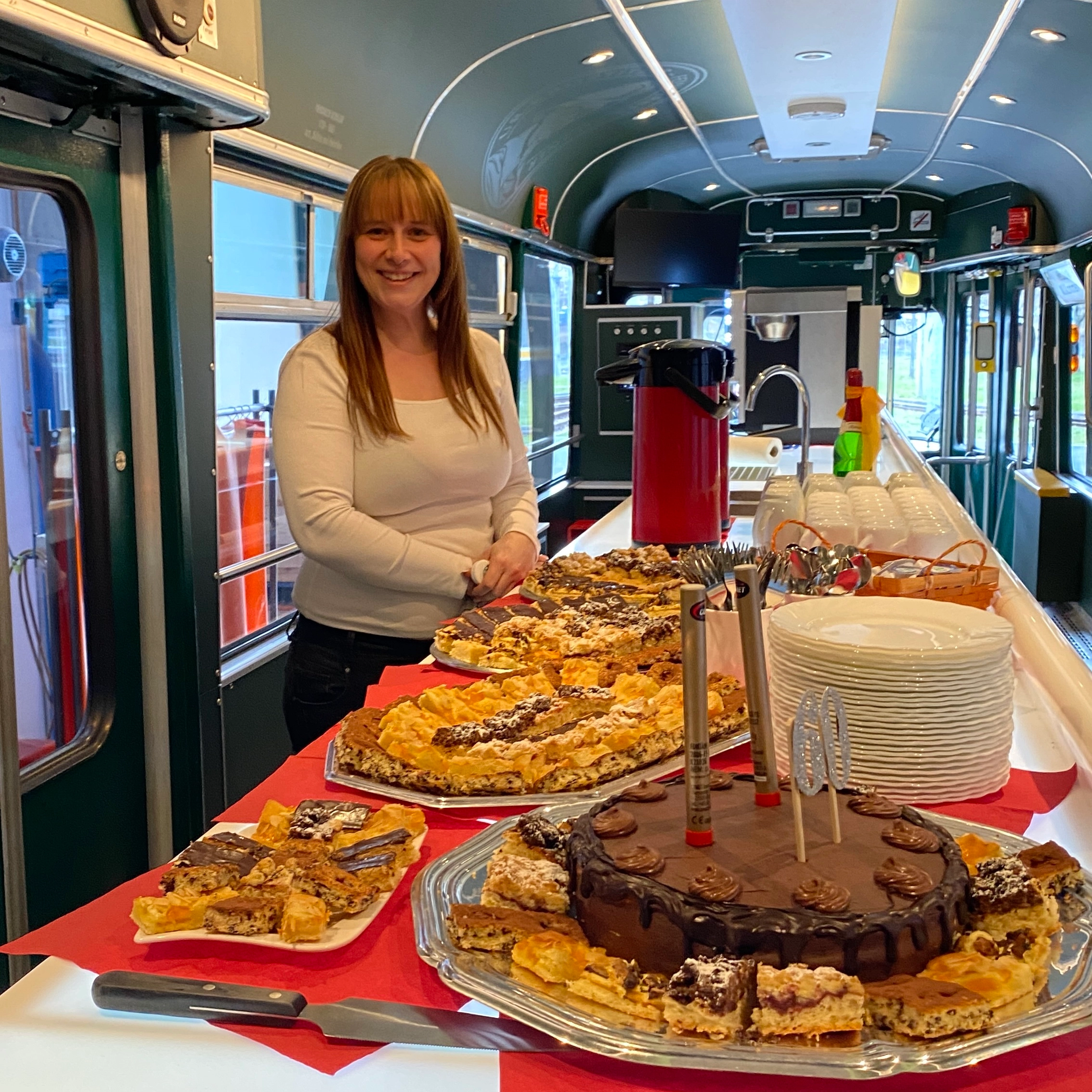 Ein Kuchenbuffet auf dem Tresen in der Ur-Krostitzer Partybahn. Im Hintergrund ist eine Frau zu sehen.