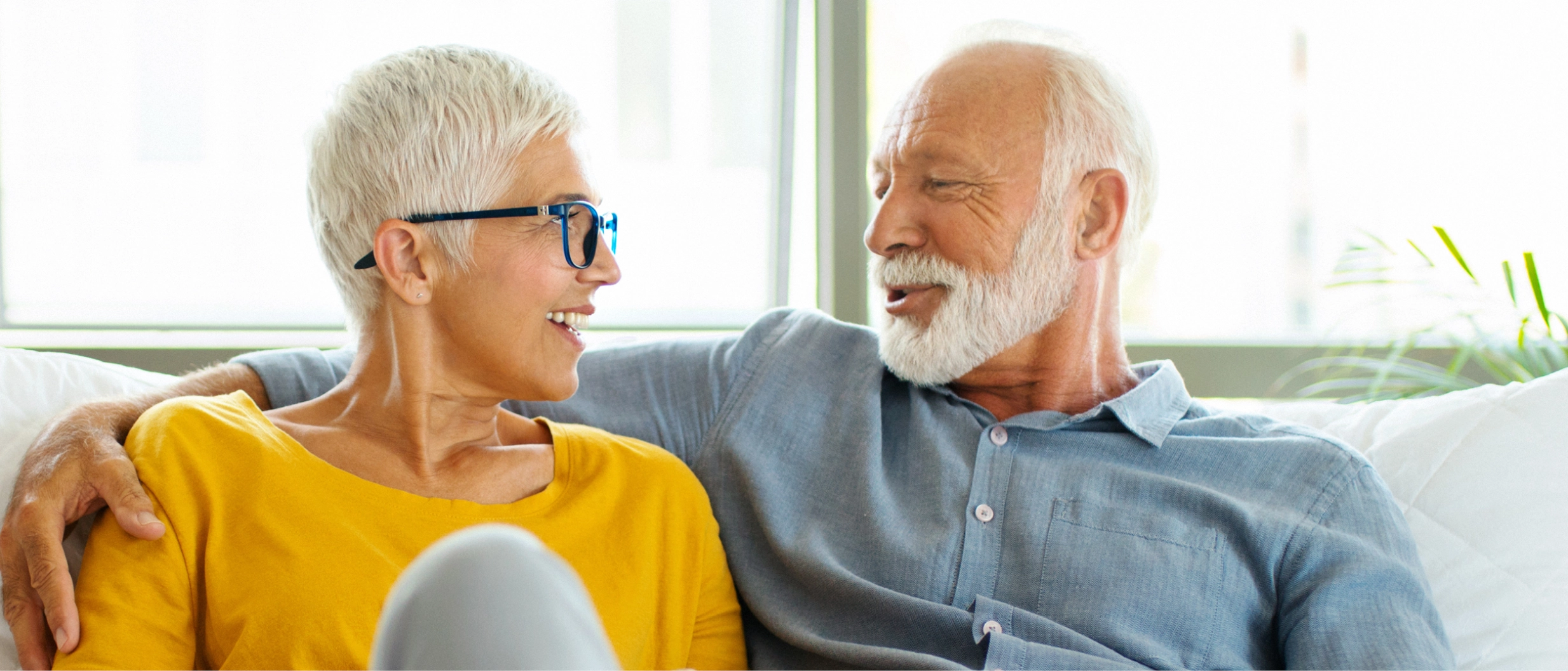 Ein Ehepaar sitzt Arm in Arm auf einem Sofa