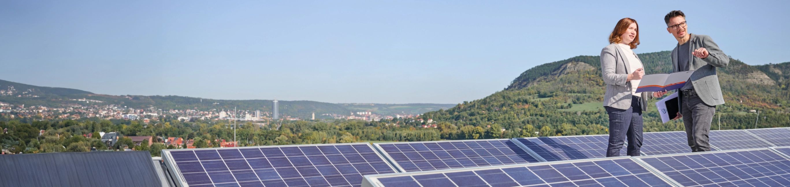 Zwei Personen stehen auf einem Dach mit Solarzellen