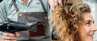 Friseur föhnt die Haare einer Kundin