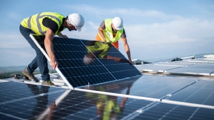 Zwei Personen befestigen Solarzellen auf einem Dach