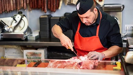 Fleischer schneidet an der Theke Fleisch
